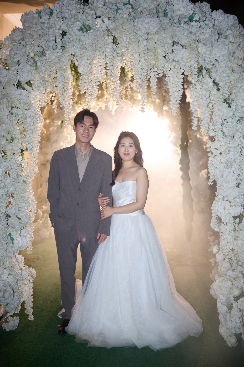 赵成成和张晴在白色花拱下的婚纱照